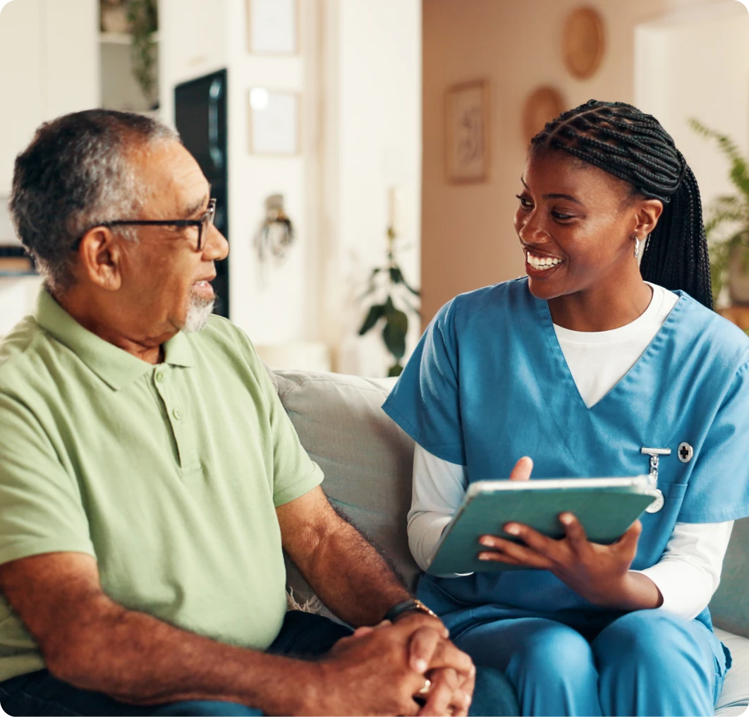 Caregiver holding a tablet, talking to man.